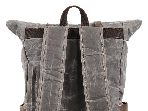 Close-up of padded shoulder straps and a carry handle on the back of a waxed canvas backpack