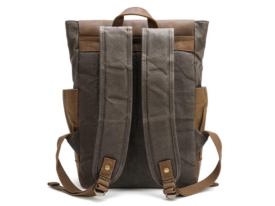 Back of a waxed canvas backpack showing adjustable shoulder straps and a leather carry handle