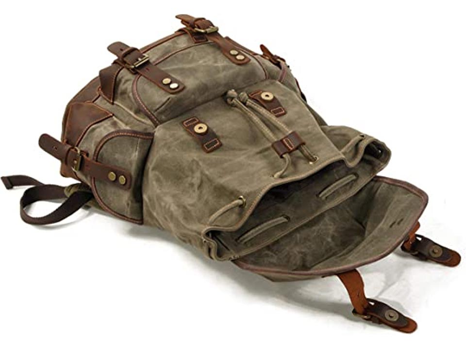 Army green waxed canvas backpack lying with its leather-trimmed canvas flap open and drawstring opening visible