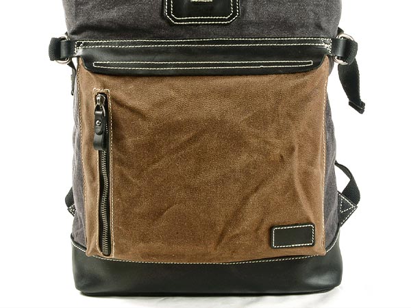 Front zipper pockets on the leather panel of a waxed canvas roll top backpack