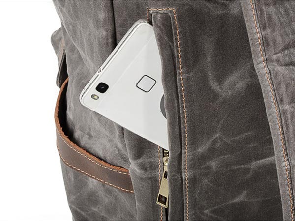 Phone stored in the hidden back zipper pocket of a waxed canvas backpack