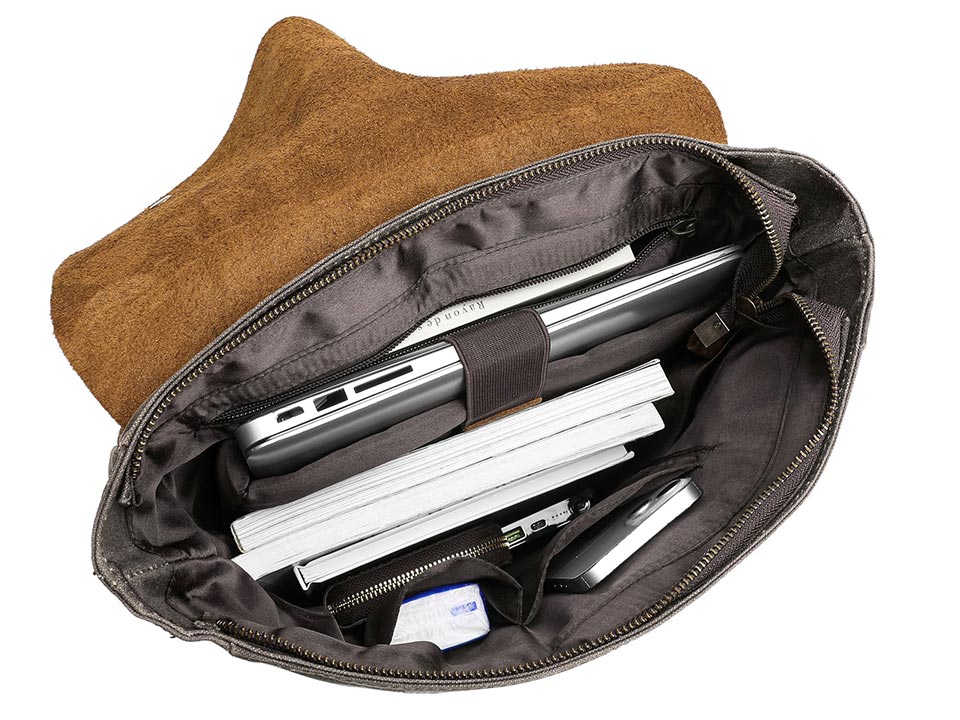 Open waxed canvas backpack showing a secured laptop, books and smaller items in its inner pockets