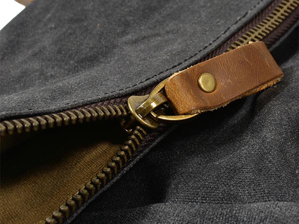 Close-up of a zipper and riveted leather zipper pull on a waxed canvas backpack