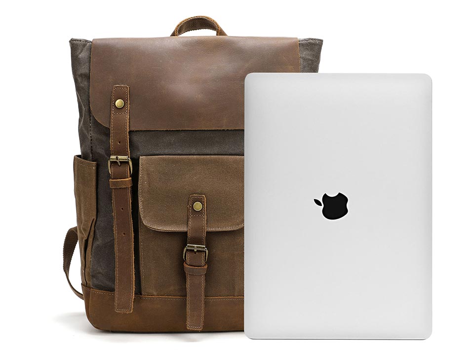 Waxed canvas backpack with a leather flap beside a laptop for size comparison