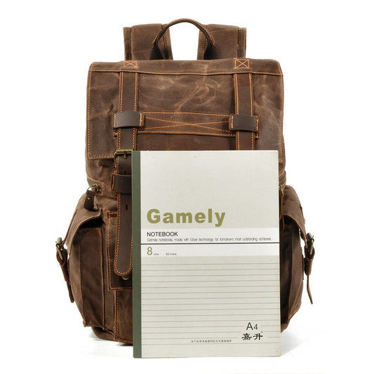 Coffee waxed canvas backpack behind a notebook for size comparison.