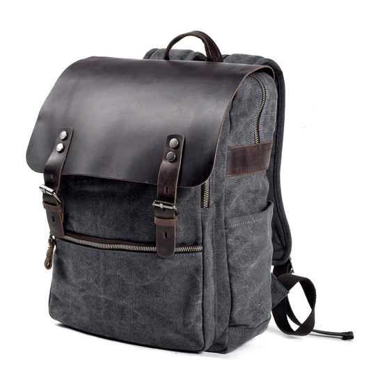 Three-quarter view of the gray canvas backpack showing its leather flap and side pocket