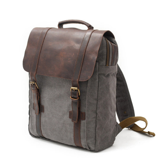 Three-quarter view of the Gray canvas backpack and its leather top handle.