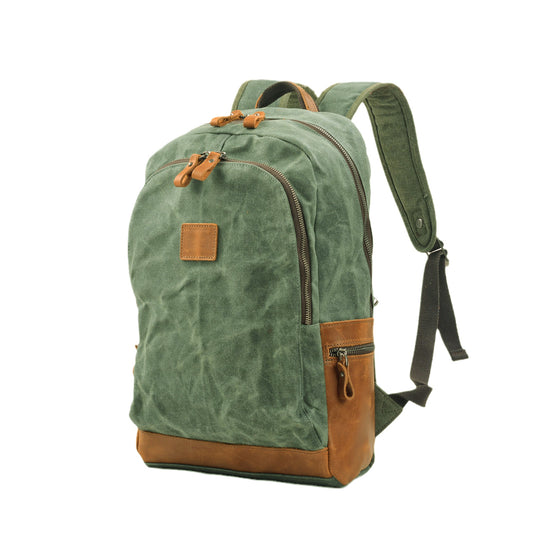 Lake green waxed canvas backpack at an angle, showing leather side pocket and padded shoulder strap.