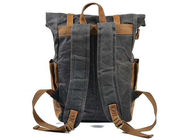 Back of a waxed canvas backpack showing adjustable shoulder straps and a leather carry handle