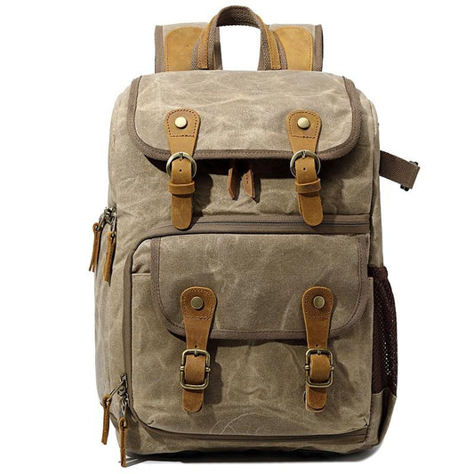 Khaki waxed canvas camera backpack with leather buckle straps and a zippered front compartment