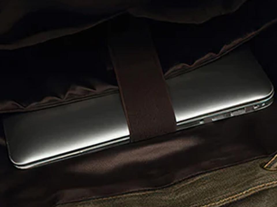 Laptop secured in the padded sleeve of an army green waxed canvas backpack