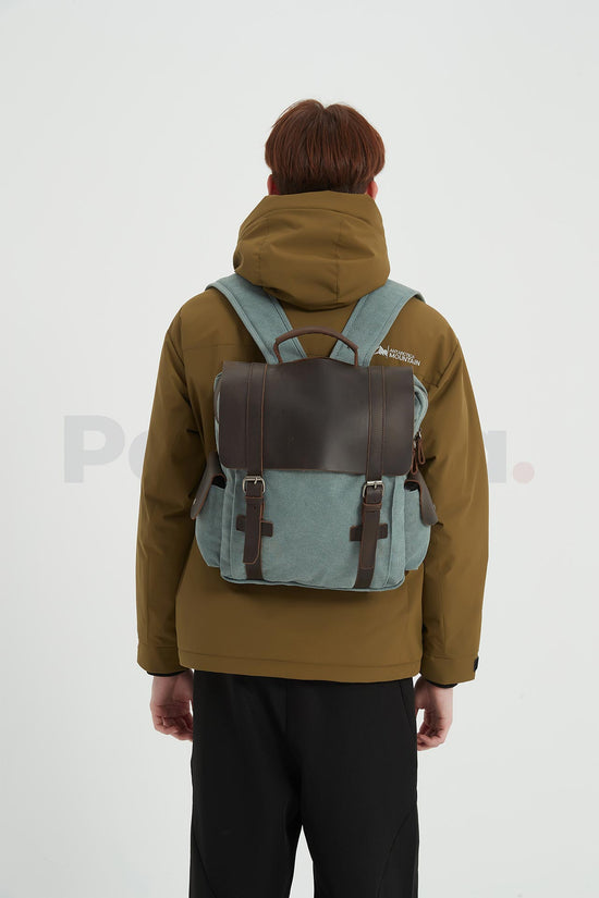 Rear view of a man wearing a blue waxed canvas backpack with a leather flap