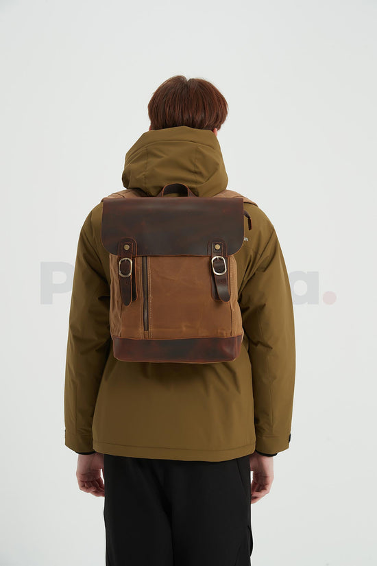 Rear view of a man wearing a khaki waxed canvas backpack with a leather flap