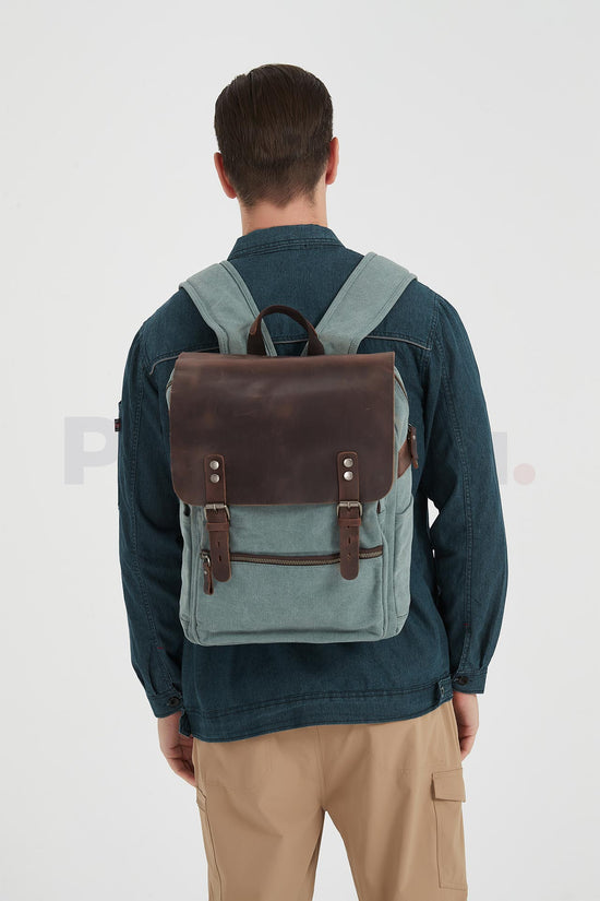 Rear view of a man wearing a lake green canvas backpack with a leather flap