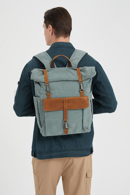 Rear view of a man wearing a blue waxed canvas roll top backpack