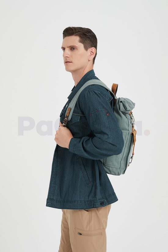 Side view of a man wearing a waxed canvas roll top backpack over both shoulders