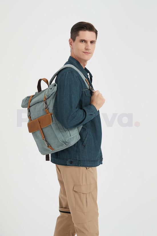 Side view of a man wearing a blue waxed canvas roll top backpack