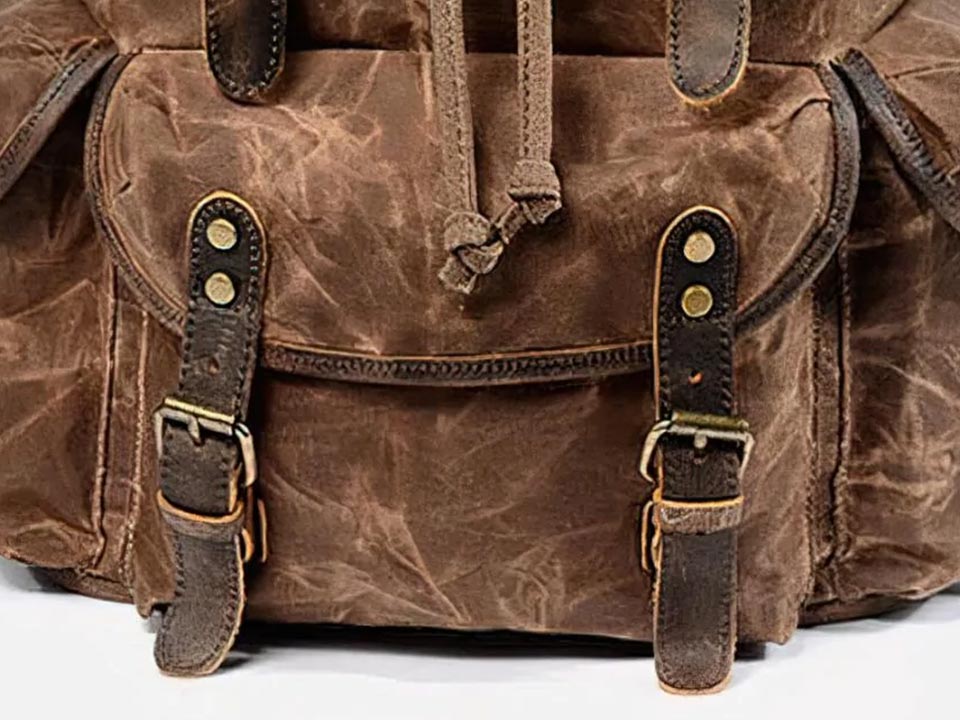 Front pocket of a coffee waxed canvas backpack with leather straps and a zipper closure