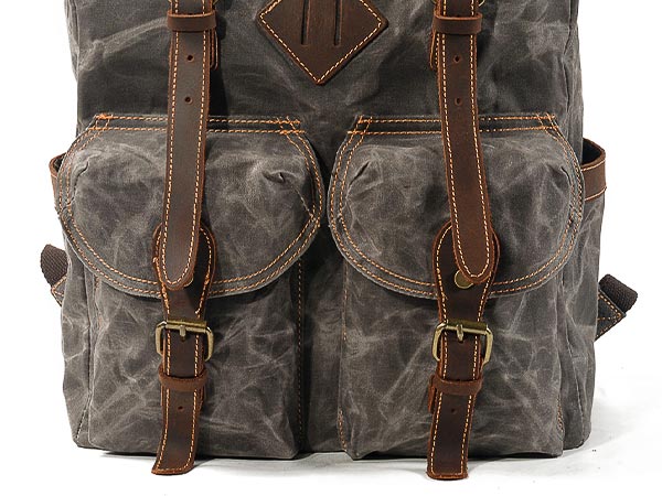 Twin front pockets with leather buckle straps on a waxed canvas backpack