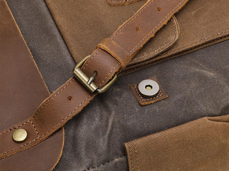 Leather buckle strap and magnetic snap closure on a waxed canvas backpack