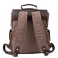 Back of coffee waxed canvas backpack with padded shoulder straps and leather-reinforced attachment points.