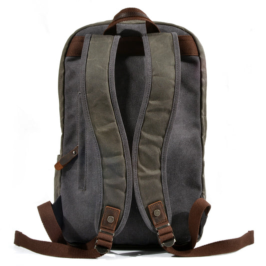 Back of army green waxed canvas backpack with padded shoulder straps and concealed zip pocket.