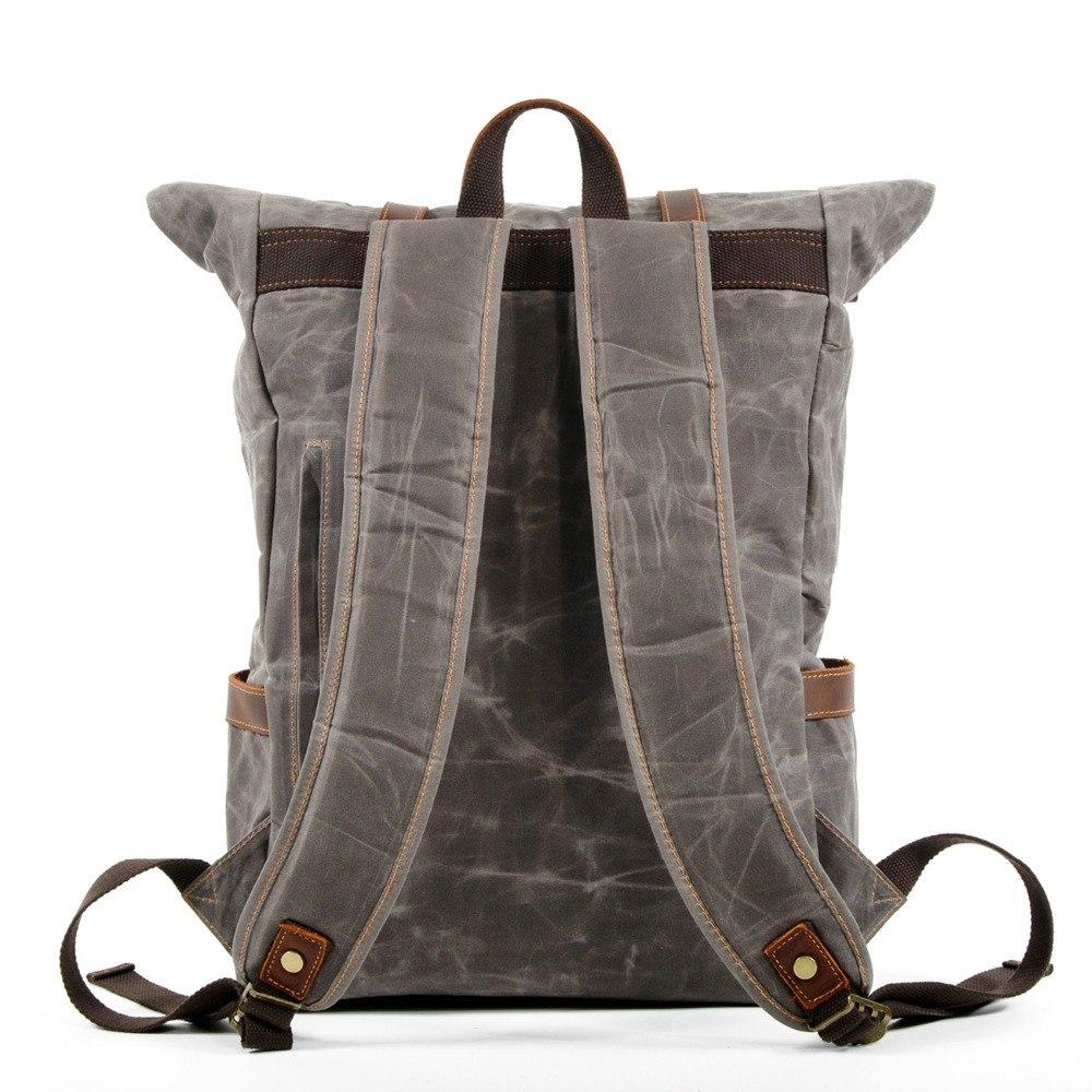 Back of gray waxed canvas backpack with padded shoulder straps, metal adjusters and reinforced attachment tabs.