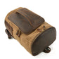 Backpack lying flat to show its zippered base and long leather front handle