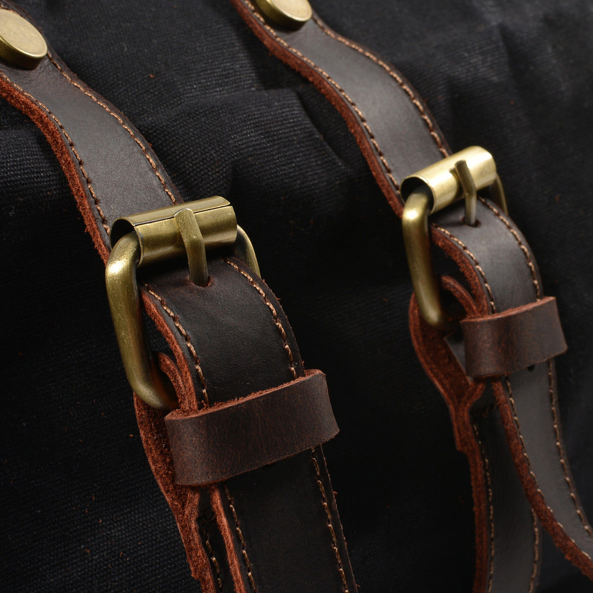 Close-up of the brass buckles on the black backpack's front straps
