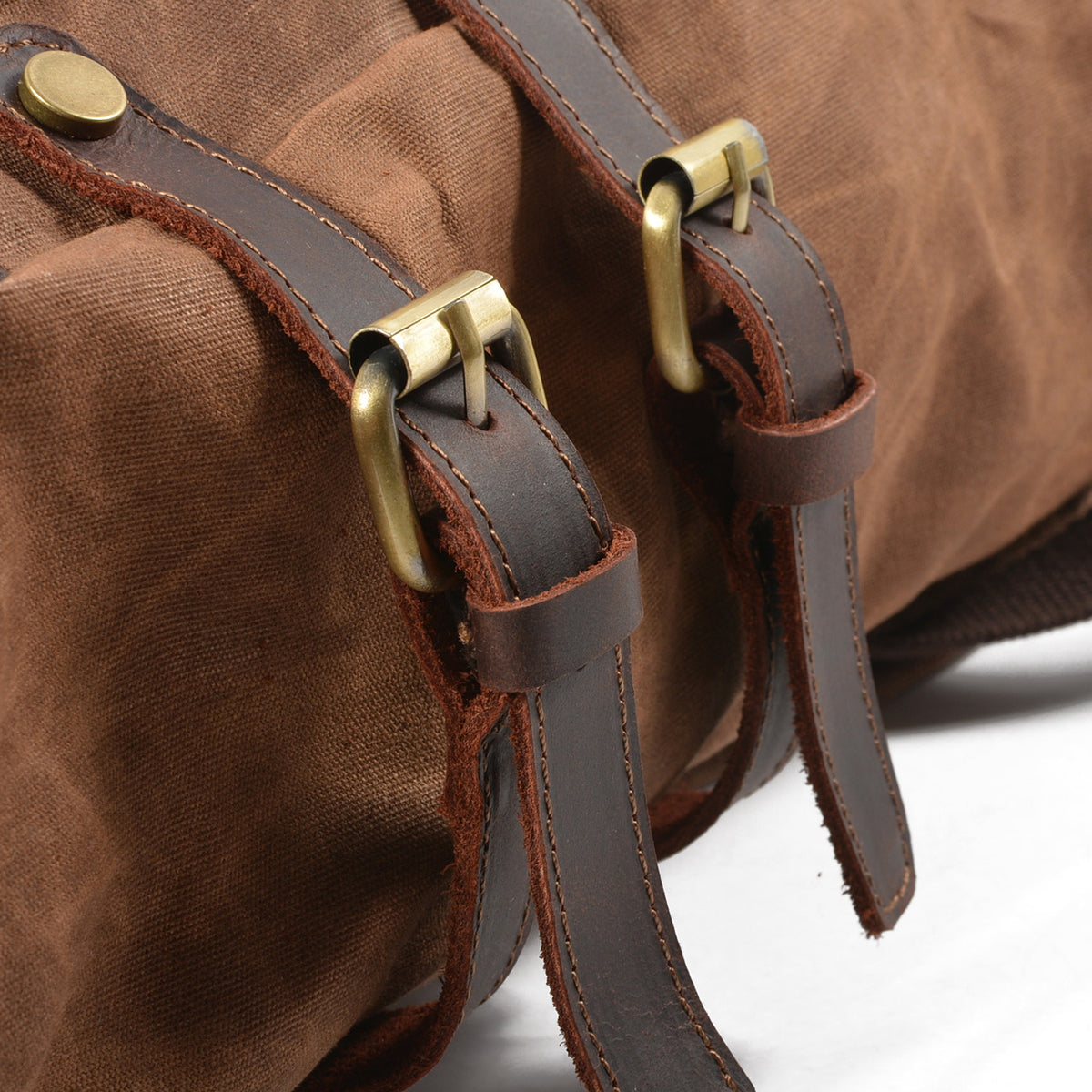 Close-up of brass buckles on the Brown backpack's leather straps.