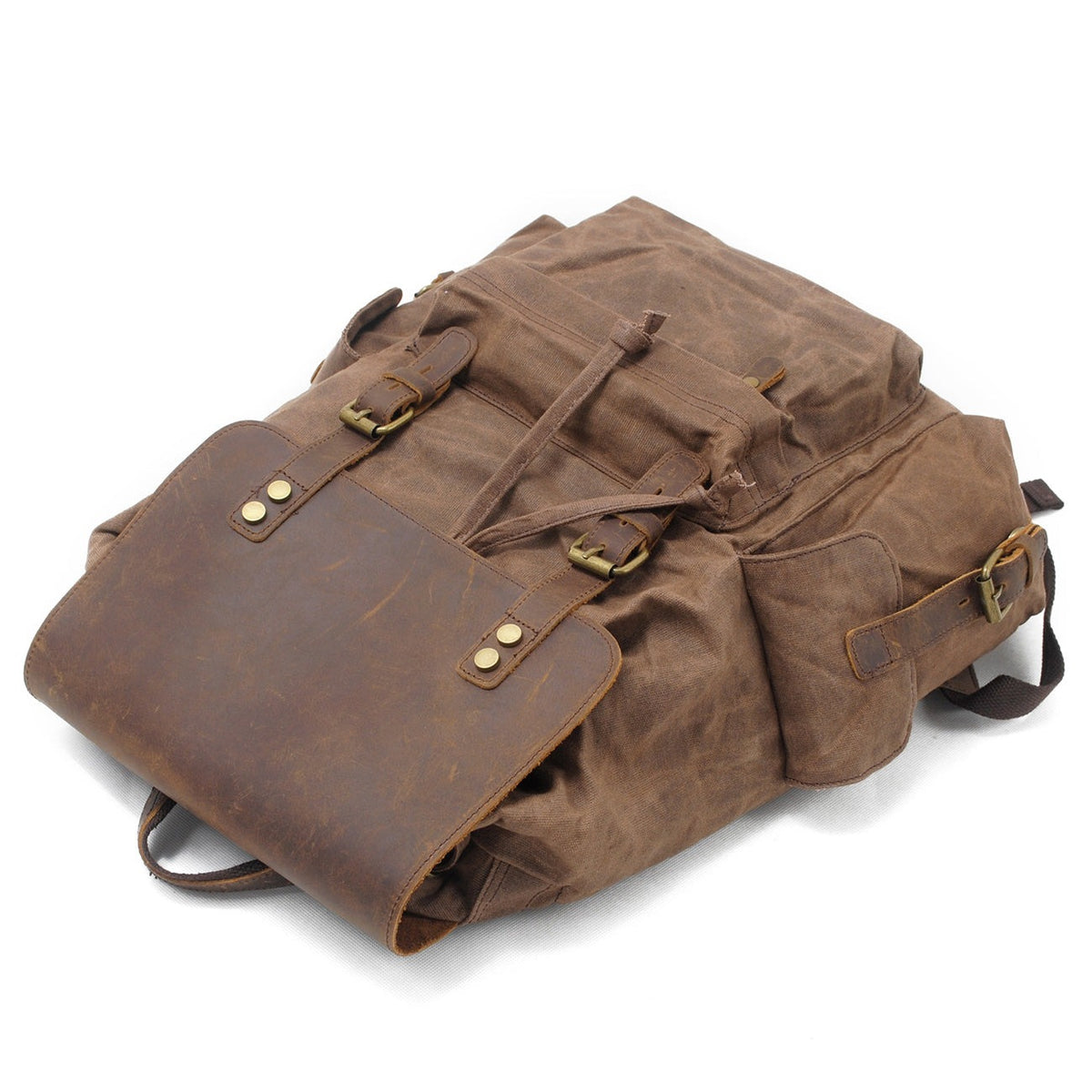 Brown waxed canvas backpack lying flat with the flap closed