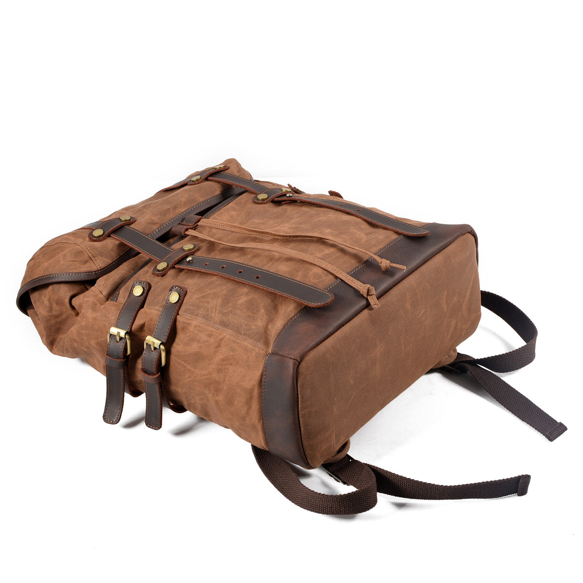 Brown waxed canvas backpack resting on its back with the front flap closed.