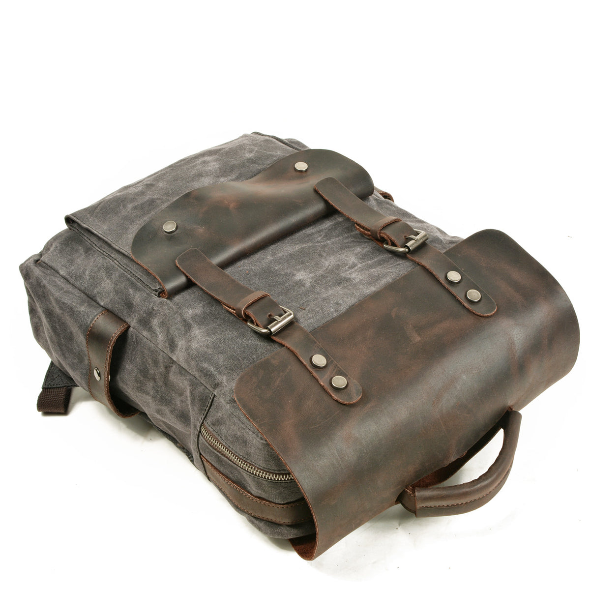 Gray backpack lying on its back with the leather flap buckled