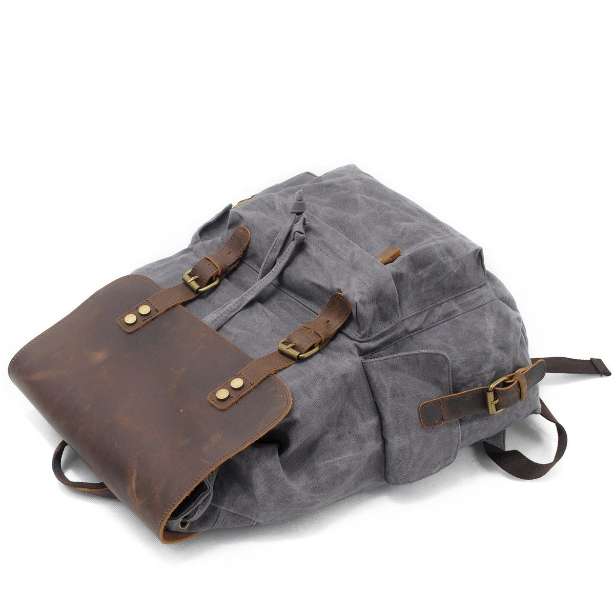 Gray waxed canvas backpack lying flat with the flap buckled