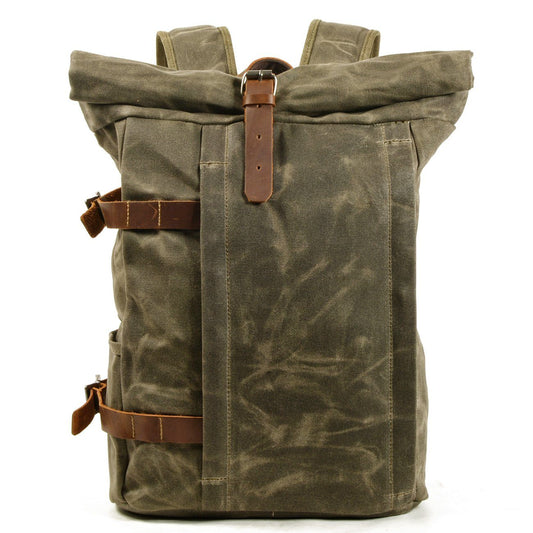 Front of army green waxed canvas roll top backpack with leather buckle strap and vertical front zip pocket.