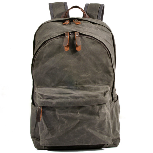 Front of army green waxed canvas backpack with rounded zip top and large front pocket.