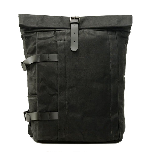 Front of black waxed canvas roll top backpack with leather buckle strap and vertical front zip pocket.