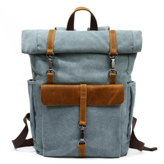 Blue waxed canvas roll top backpack with a leather front flap and snap hook closures