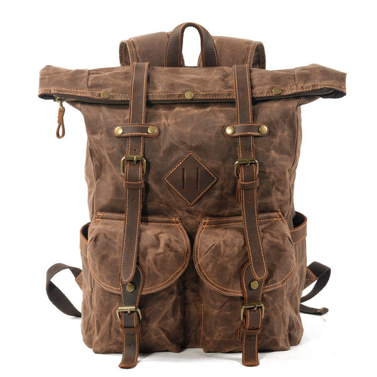 Front of coffee waxed canvas roll top backpack with leather buckle straps and twin flap pockets.