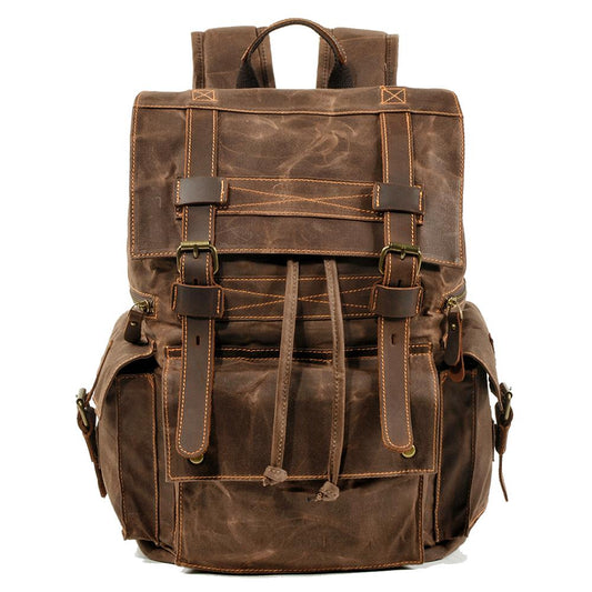 Front of coffee waxed canvas backpack with drawstring closure, leather buckle straps and flap pockets.