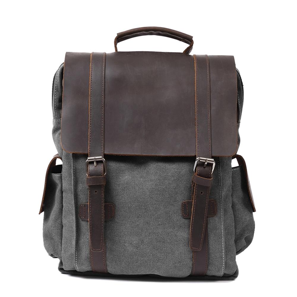 Front of gray waxed canvas backpack with broad leather flap and twin buckle straps.