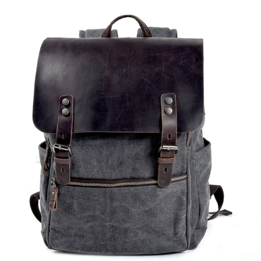 Gray canvas laptop backpack with a crazy horse leather flap, buckle straps and front zip pocket