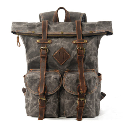 Front of gray waxed canvas roll top backpack with leather buckle straps and twin flap pockets.