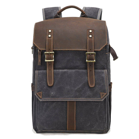 Front of gray waxed canvas backpack with leather flap, twin buckle straps and front pocket.