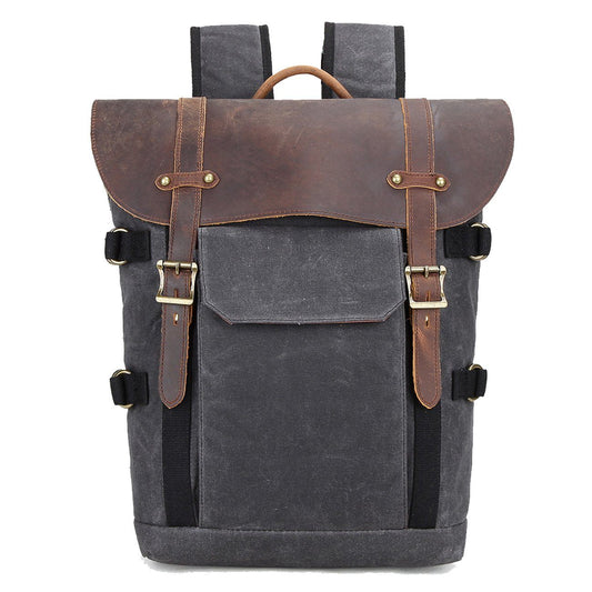 Front of gray waxed canvas backpack with wide leather flap, twin buckle straps and outer pocket.