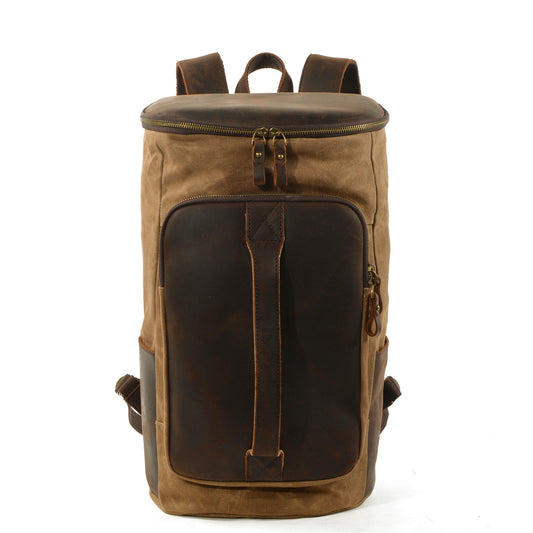 Khaki waxed canvas travel backpack with a large leather front pocket and zippered top