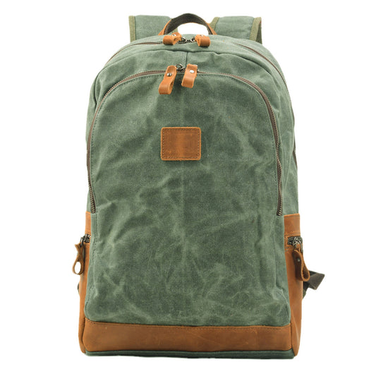Front of lake green waxed canvas backpack with leather base trim and paired zipper pulls.
