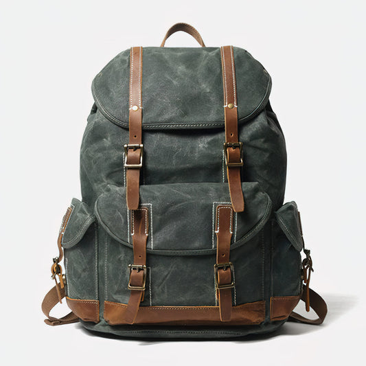 Front of lake green waxed canvas backpack with leather buckle straps, flap pockets and reinforced base.