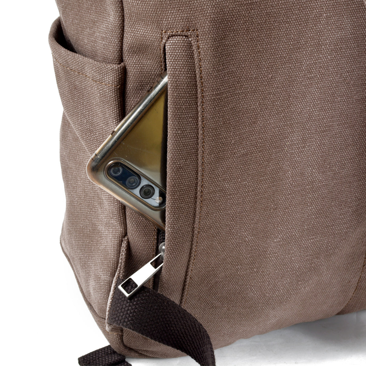 Phone resting in the backpack's rear zip pocket with the leather pull tab visible