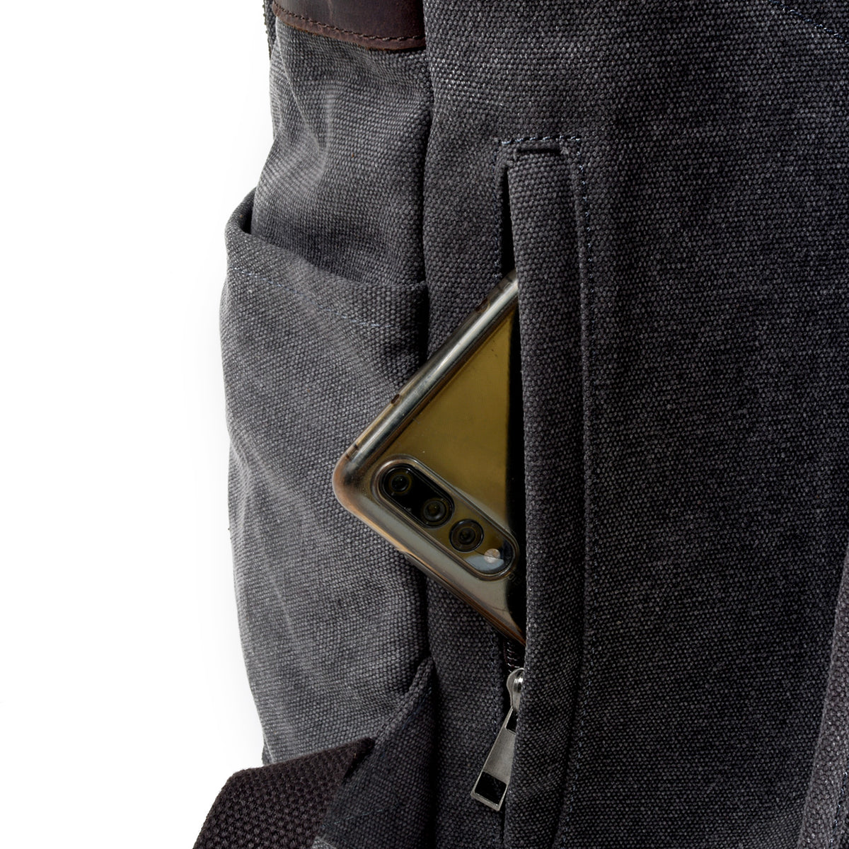 Rear zip pocket holding a phone beside the backpack's shoulder strap